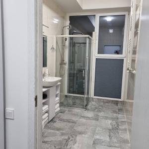 a white bathroom with a sink and a shower at Glass Cube Hotel in Chişinău