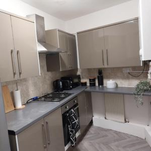 a kitchen with white cabinets and a stove top oven at 4 Double Bedroom House in Accrington sleeps 6 in Accrington +20 photos