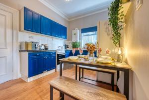 uma cozinha com armários azuis e uma mesa de madeira em Exquisite Flat - Parking - Sleeps 9 em Bristol