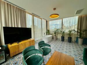 Abanotubani Boutique hotel في تبليسي: غرفة معيشة مع تلفزيون بشاشة مسطحة وكراسي خضراء