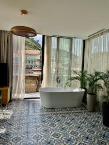 Abanotubani Boutique hotel في تبليسي: حوض استحمام في حمام مع نافذة كبيرة