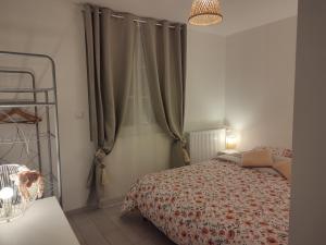 a bedroom with a bed and a window with curtains at La petite maison in Mesnil-Saint-Nicaise
