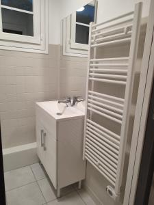 a white bathroom with a sink and a mirror at La petite maison in Mesnil-Saint-Nicaise
