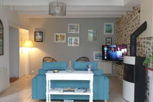 a living room with a blue couch and a tv at Les Coquelicots classé 3 étoiles in Paimpol