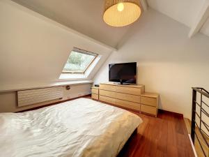 een slaapkamer met een bed en een flatscreen-tv bij Suite duplex salon-bureau & chambre en mezzanine in Opprebais