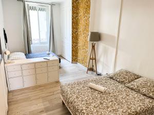 a bedroom with a bed and a dresser and a window at Suite Magelan in Villeurbanne