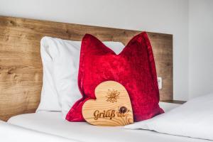 a red pillow sitting on a bed with a red blanket at Au Pension in Söll