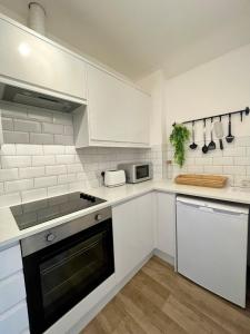 a kitchen with white cabinets and a stove top oven at Central, Chic Apartment in Bournemouth