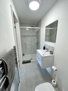 a white bathroom with a shower and a sink at Central, Chic Apartment in Bournemouth