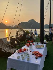 Bông Hà Nội hostel في هانوي: طاولة مع الطعام وكؤوس النبيذ على متن قارب