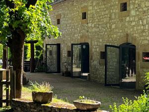 Maison de famille في Camboulit: مبنى حجري بأبواب زجاجية وشجرة
