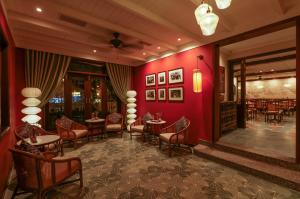 een restaurant met rode muren en tafels en stoelen bij Cozy Savvy Boutique Hotel Hoi An in Hội An