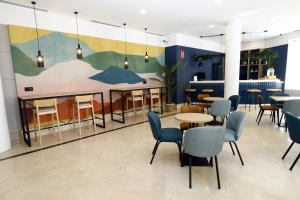 hol ze stołami i krzesłami oraz malowidłem ściennym w obiekcie Travelodge Madrid Coslada Aeropuerto w mieście Coslada