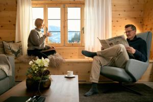 a man and a woman sitting in chairs in a living room at Casa Mulania in Laax