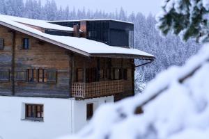 a wooden house with snow on the roof at Casa Mulania in Laax