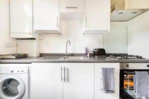 a white kitchen with a sink and a washing machine at Garden Flat in central location in London