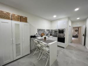 una cucina con armadi bianchi e un'isola cucina con sgabelli. di Centro Estudio Trinidad Málaga 3 a Málaga