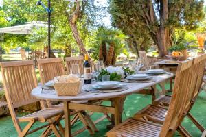 Alghero prestigiosa antica dimora indipendente con piscina per 9 persone في ألغيرو: طاولة خشبية مع كراسي وطاولة مع زجاجات النبيذ