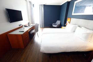 Habitación de hotel con 2 camas, escritorio y TV. en Travelodge Madrid Coslada Aeropuerto, en Coslada