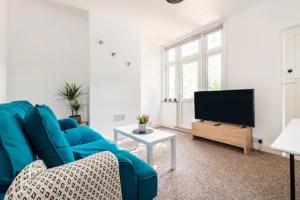 a living room with a blue couch and a tv at Garden Flat in central location in London