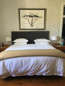 een slaapkamer met een groot bed met witte lakens en kussens bij Just Joey Lodge in Stellenbosch