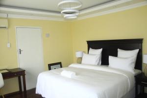 1 dormitorio con 1 cama blanca grande con almohadas blancas en Suprime Hotels and Conference, en Pietermaritzburg