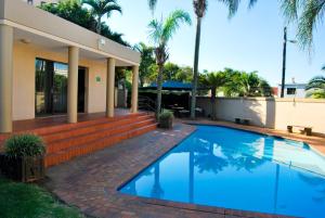 a swimming pool in front of a house with palm trees at 7 The Shades Umhlanga Rocks in Durban