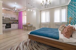 a bedroom with a large bed and a kitchen at Expo Promenade Уютная квартира возле Expo in Prigorodnyy