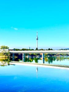 a river with a bridge and a tower in the background at Ursula Rosé Collection an der Donau in Vienna