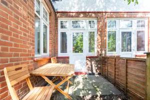 a patio with a wooden bench and a brick wall at Garden Flat in central location in London