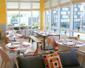 un restaurante con mesas, sillas y ventanas en Séjours & Affaires Paris-Vitry, en Vitry-sur-Seine