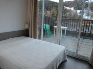 um quarto com uma cama e vista para uma varanda em Joli T2 au coeur de Praloup 1600 em Uvernet
