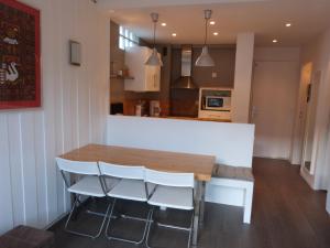 uma cozinha com uma mesa de madeira e cadeiras brancas em Joli T2 au coeur de Praloup 1600 em Uvernet