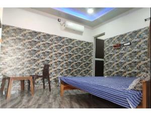 1 dormitorio con cama, mesa y pared en Eeshwar Lodge, Patnagarh, Odisha 