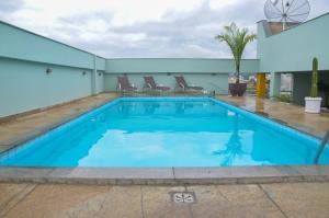 una piscina con agua azul en un edificio en Riviera Palace Hotel, en Sete Lagoas