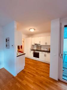 a kitchen with white cabinets and a hard wood floor at Ursula Rosé Collection an der Donau in Vienna