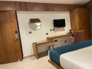 una camera da letto con un letto e una scrivania con una televisione di Hotel Emora Tree a Mysore