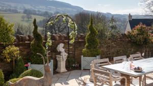 a patio with a table and chairs in a garden at Beaufort Farmhouse in Grosmont