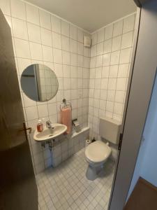 ein Badezimmer mit einem WC, einem Waschbecken und einem Spiegel in der Unterkunft Ferienwohnung Am Rathausberg in Schiffweiler
