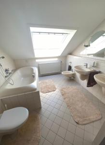 a bathroom with a tub and a toilet and a sink at Ferienwohnung Am Rathausberg in Schiffweiler