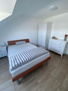 a bedroom with a bed and a white dresser at Ferienwohnung Am Rathausberg in Schiffweiler