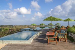 a swimming pool with chairs and tables and umbrellas at Grün Resort Uluwatu in Uluwatu