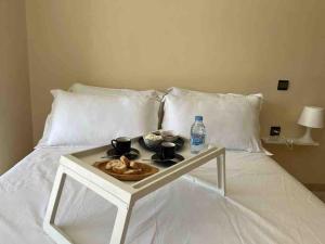 Una cama blanca con una bandeja de comida. en Logement entier et indépendant A, en Rabat
