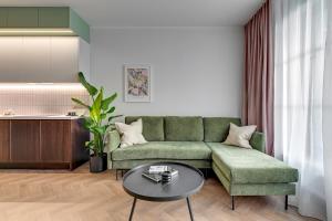 uma sala de estar com um sofá verde e uma mesa em Downtown Apartments DOKI Living - Foodhall & Parking em Gdansk