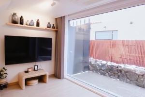 a living room with a large window and a flat screen tv at Blue Casa in Seogwipo