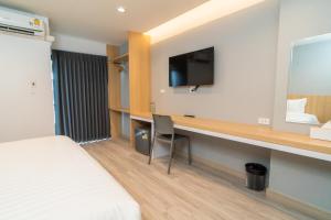 a hotel room with a desk and a tv at Goodday Hotel in Ban Nong Waeng
