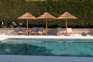 uma piscina com guarda-sóis e espreguiçadeiras e uma piscina em Malates Slow Boutique Hotel em Foz