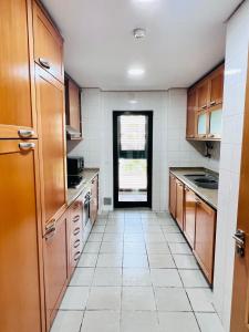 una cucina con armadi in legno e pavimento piastrellato bianco di Apartamento golf-mar a Vilamoura