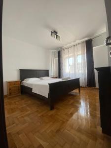 a bedroom with a bed and a wooden floor at Apartament Central Suceava in Suceava