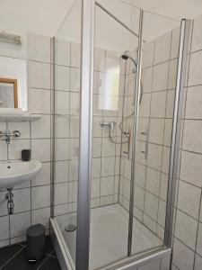 um chuveiro com uma porta de vidro ao lado de um lavatório em AMS The Gray em Spaichingen